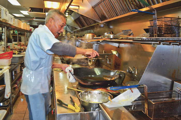 ■新瑞华厨房内，一位厨师正在使用天然气炉为客人煮菜。